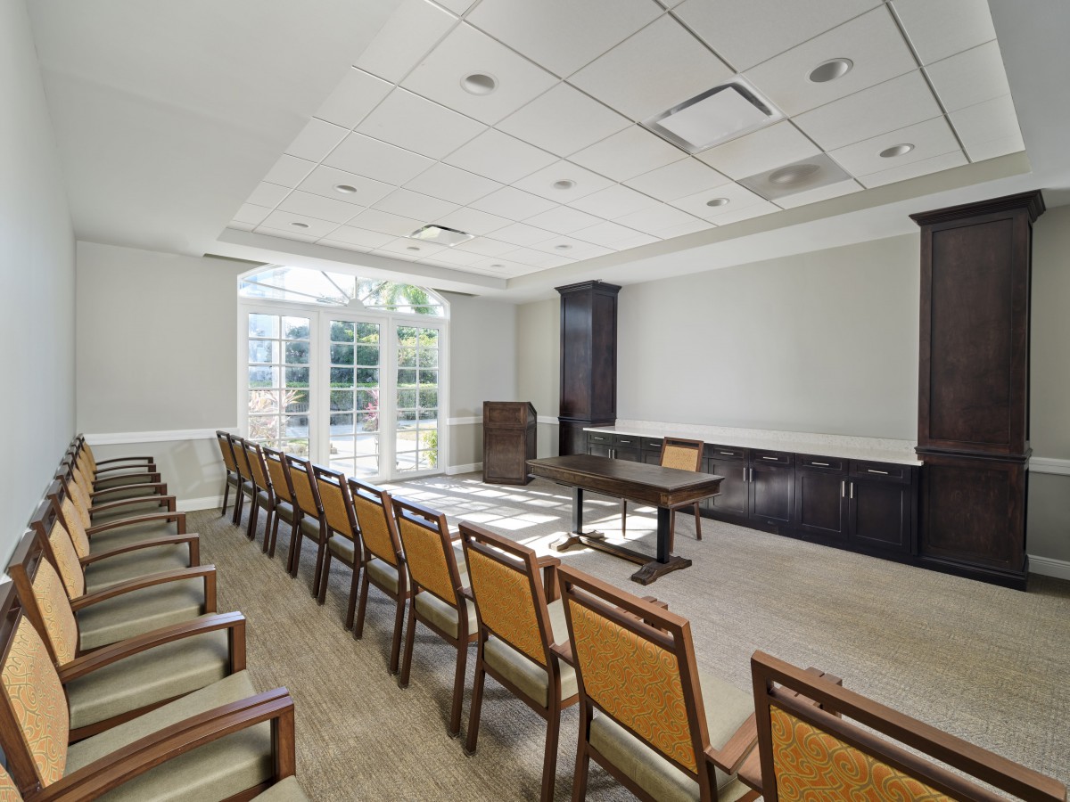 A well-lit conference room with rows of chairs and a podium at the front.