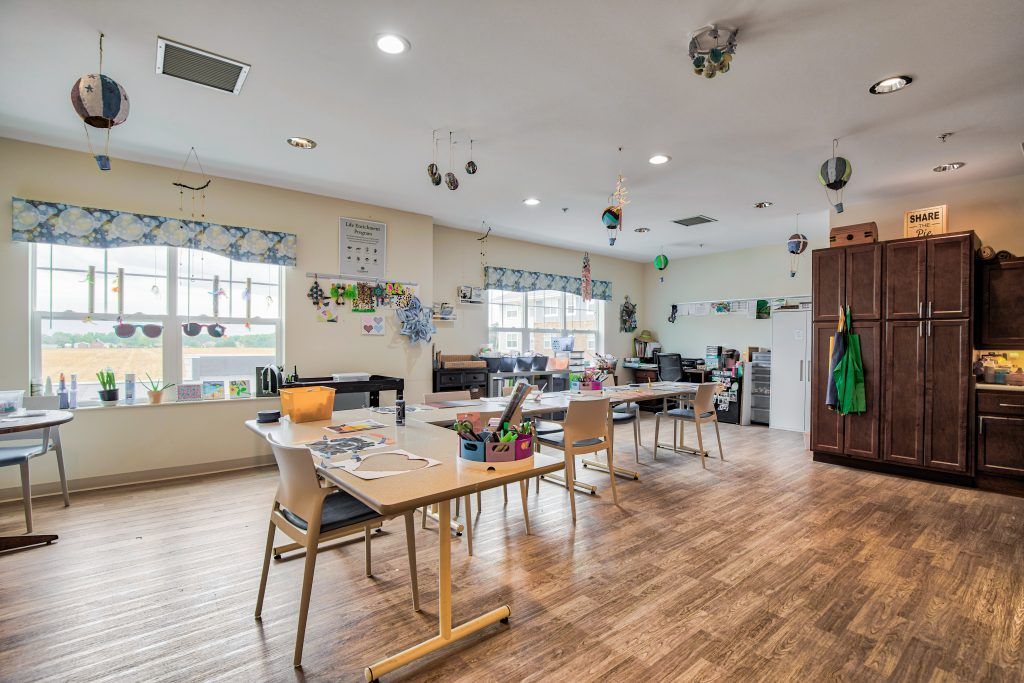 A bright and inviting classroom setup with tables and chairs, equipped with educational materials and art supplies.