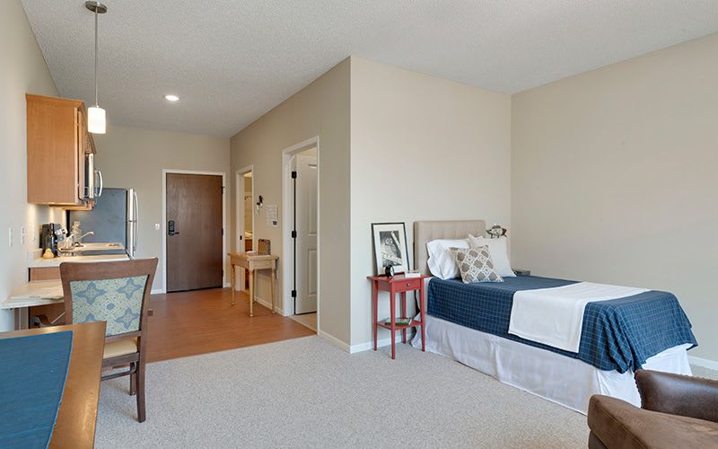A cozy and minimalist bedroom featuring a single bed, small side table, and wooden floor with neutral tones.