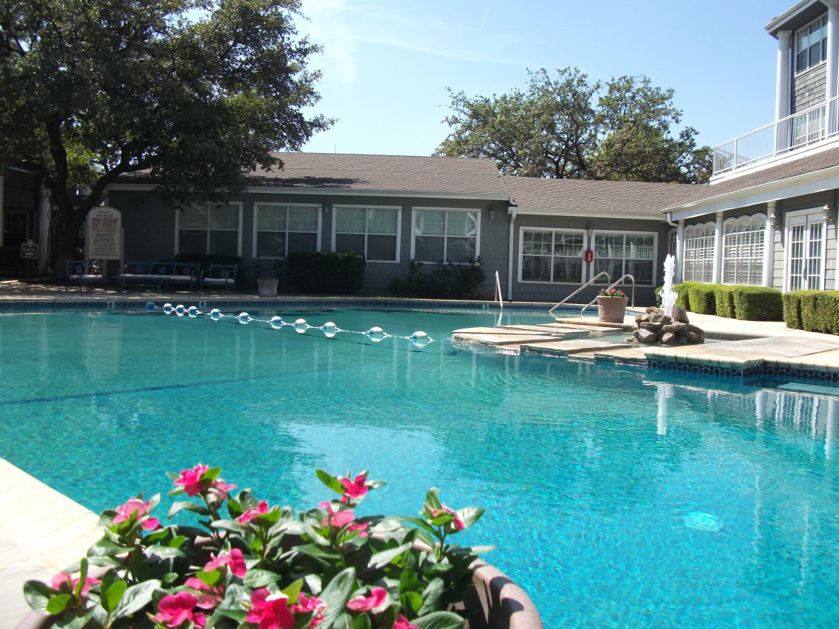 A tranquil swimming pool surrounded by residential buildings and vibrant flowers.