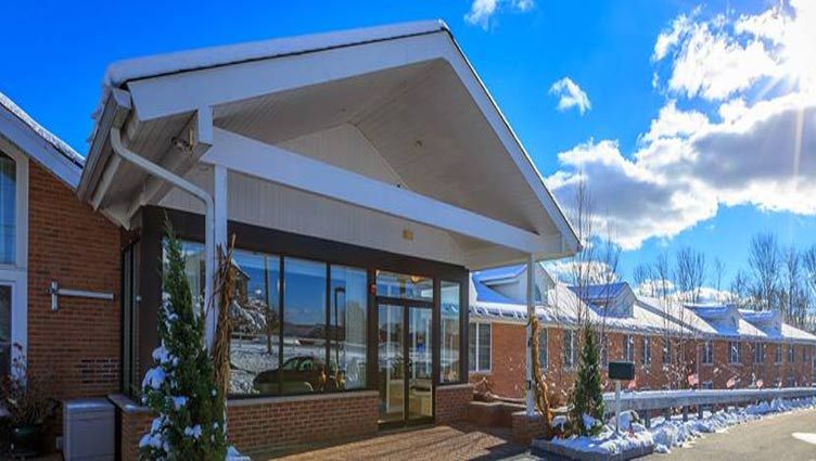 A modern building entrance with snow on the ground and a clear blue sky.