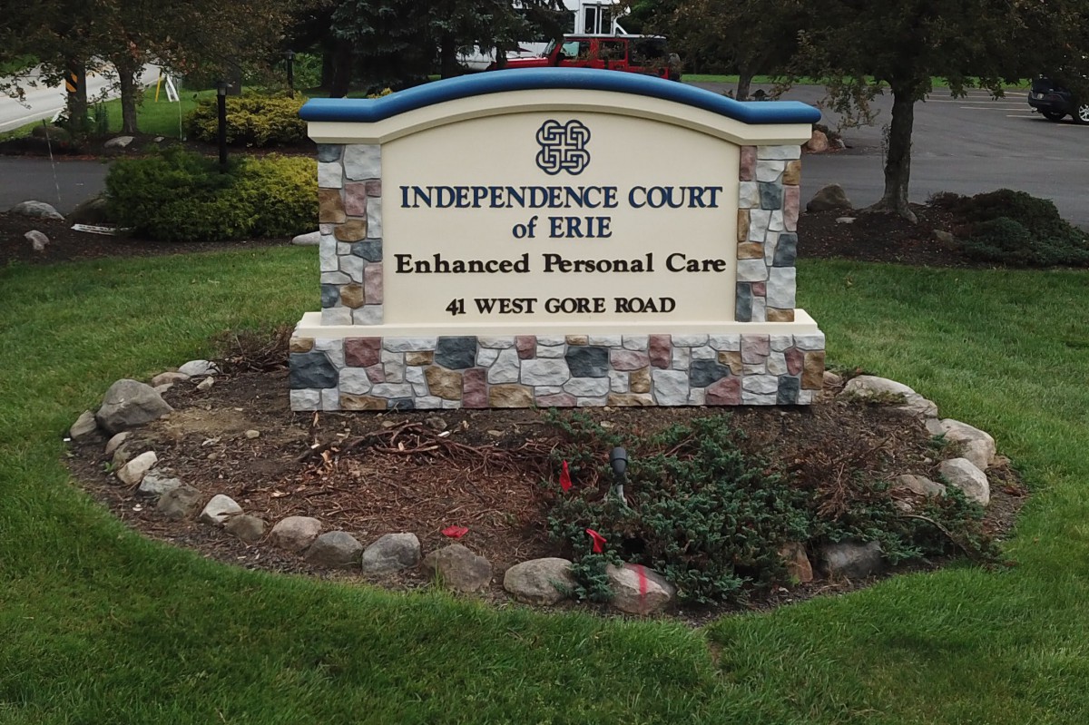 A stone sign for Independence Court of Erie Enhanced Personal Care on West Gore Road, surrounded by landscaping.