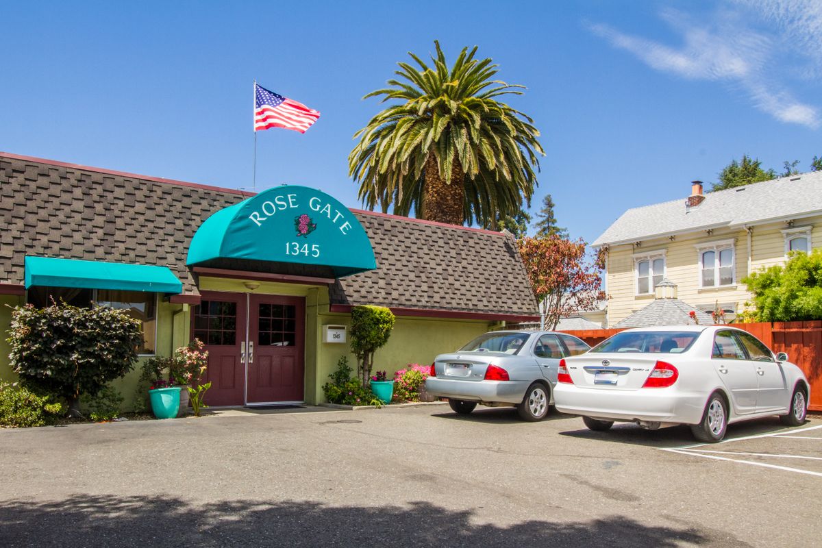 Front view of a cozy roadside motel with parked cars and an American flag.