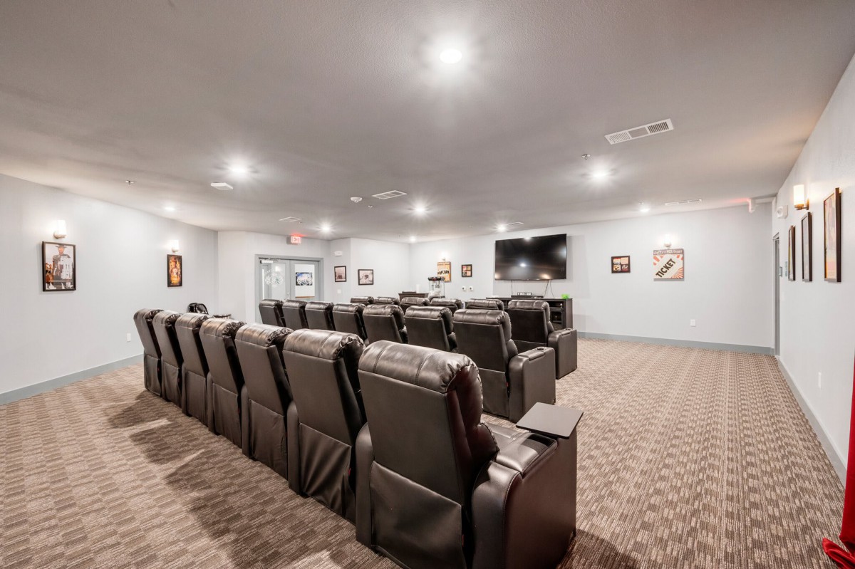 A spacious home theater with multiple rows of recliner chairs and a large screen.