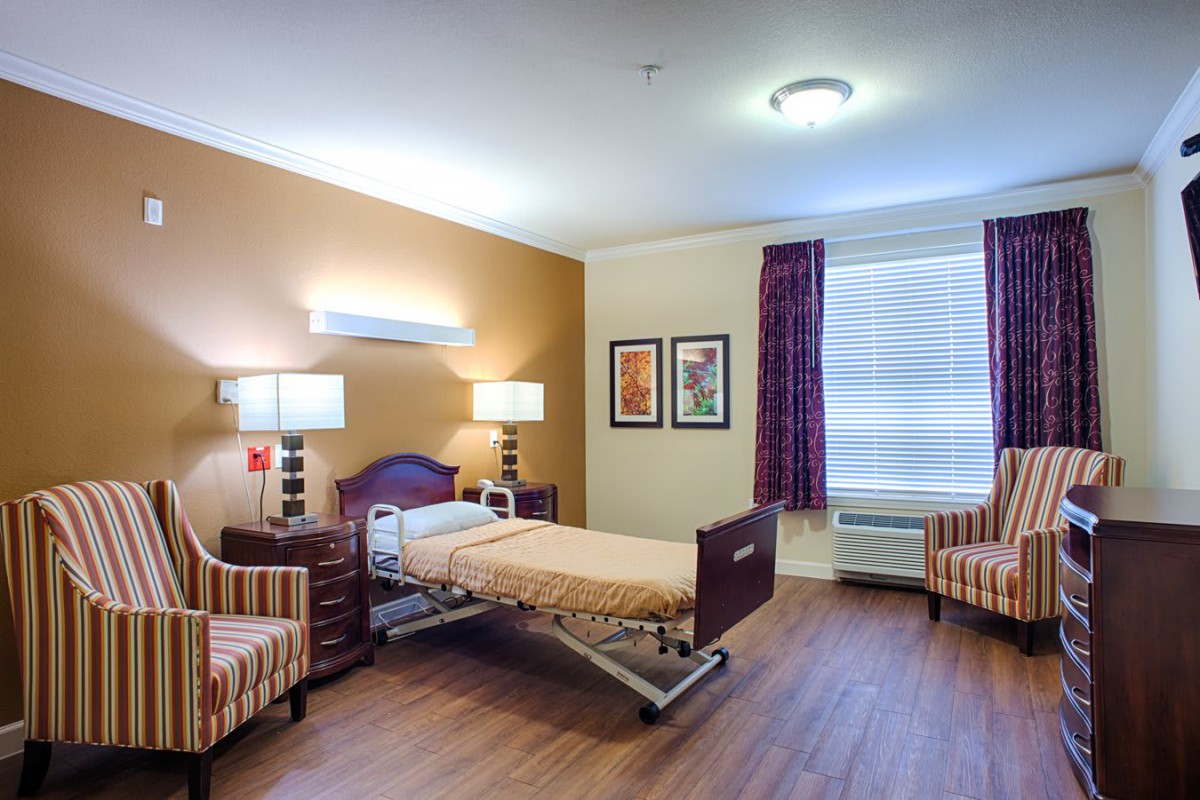 A well-appointed hospital room featuring a bed, chairs, and large window.