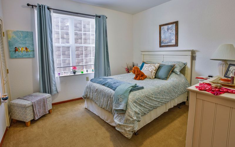 A cozy bedroom with a neatly made bed, pillows, and a window with curtains.