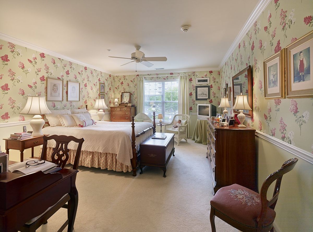 A traditional bedroom with floral wallpaper and classic furnishings.