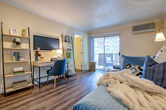 A cozy bedroom with a desk and chair, featuring a wall-mounted TV and stylish decor.