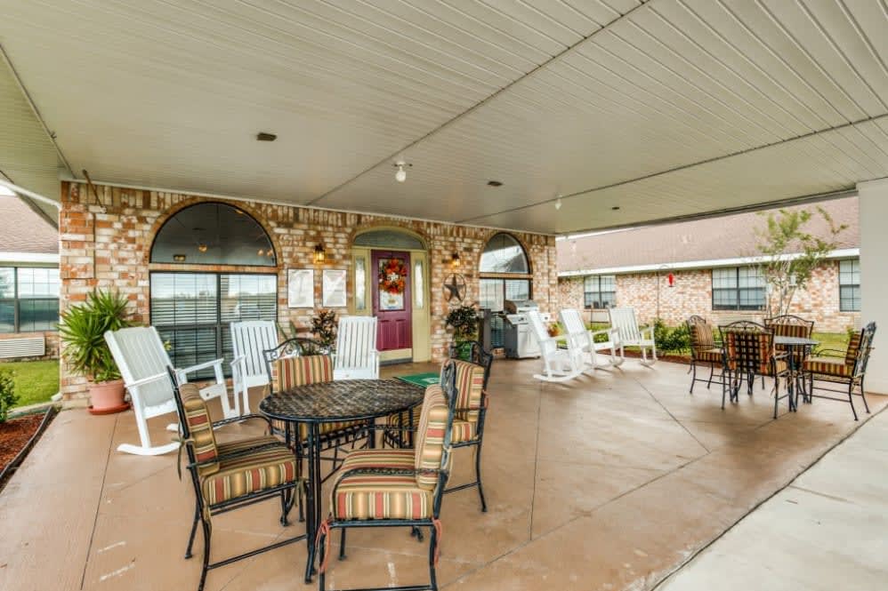 A spacious covered patio with outdoor seating and decorative brick walls.