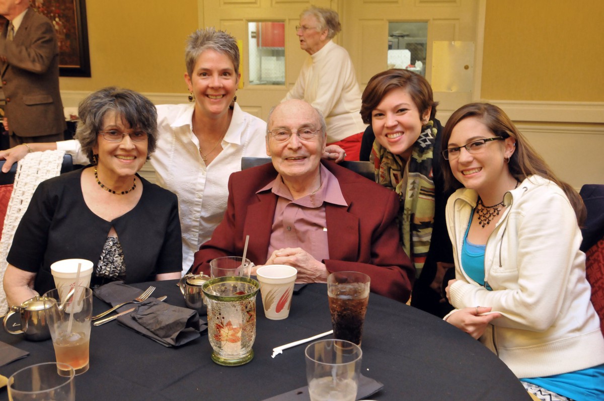 A group of five people smiling together at a dinner event.