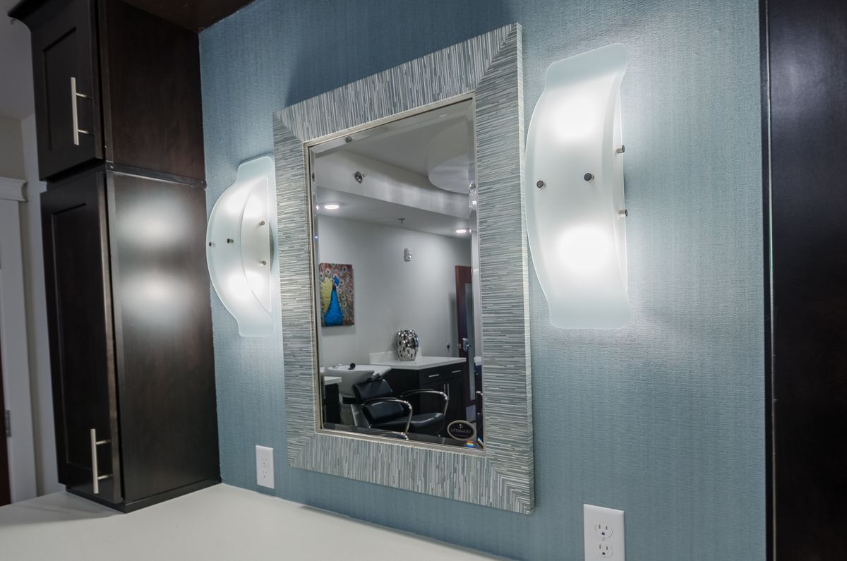 A modern interior featuring a decorative mirror with wall-mounted lights on either side.