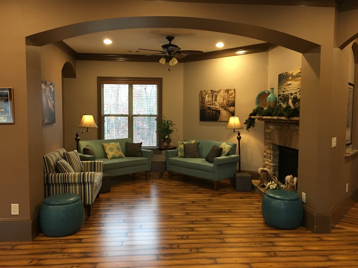 A cozy living room with teal sofas, a fireplace, and warm lighting on hardwood floors.