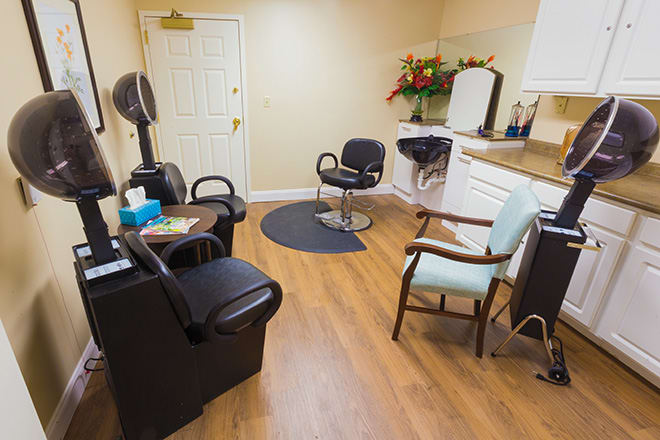 A cozy salon interior with chairs, a hairdryer, and a vanity mirror.