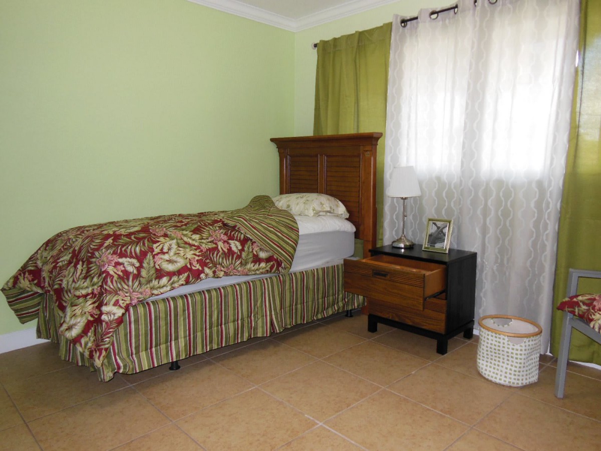 A cozy bedroom with a single bed and nightstand by the window.