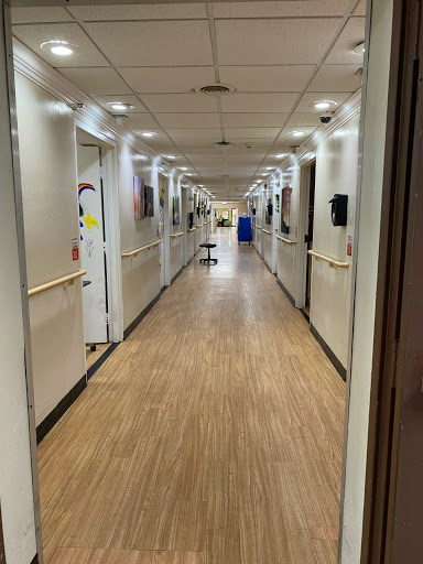A view of a hospital hallway with doors to various rooms on either side.