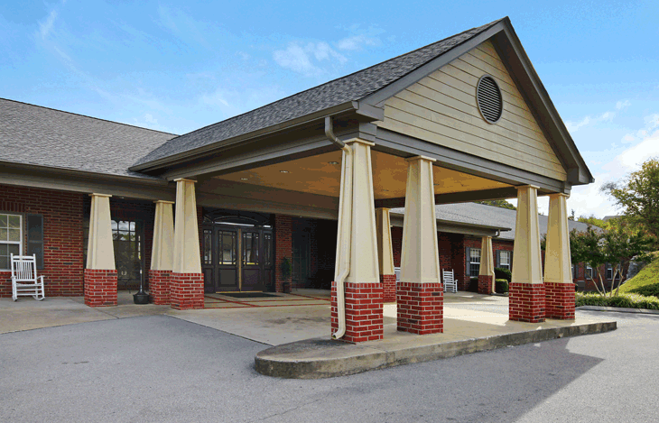 A building with a covered entrance featuring brick and siding, seen during the daytime.