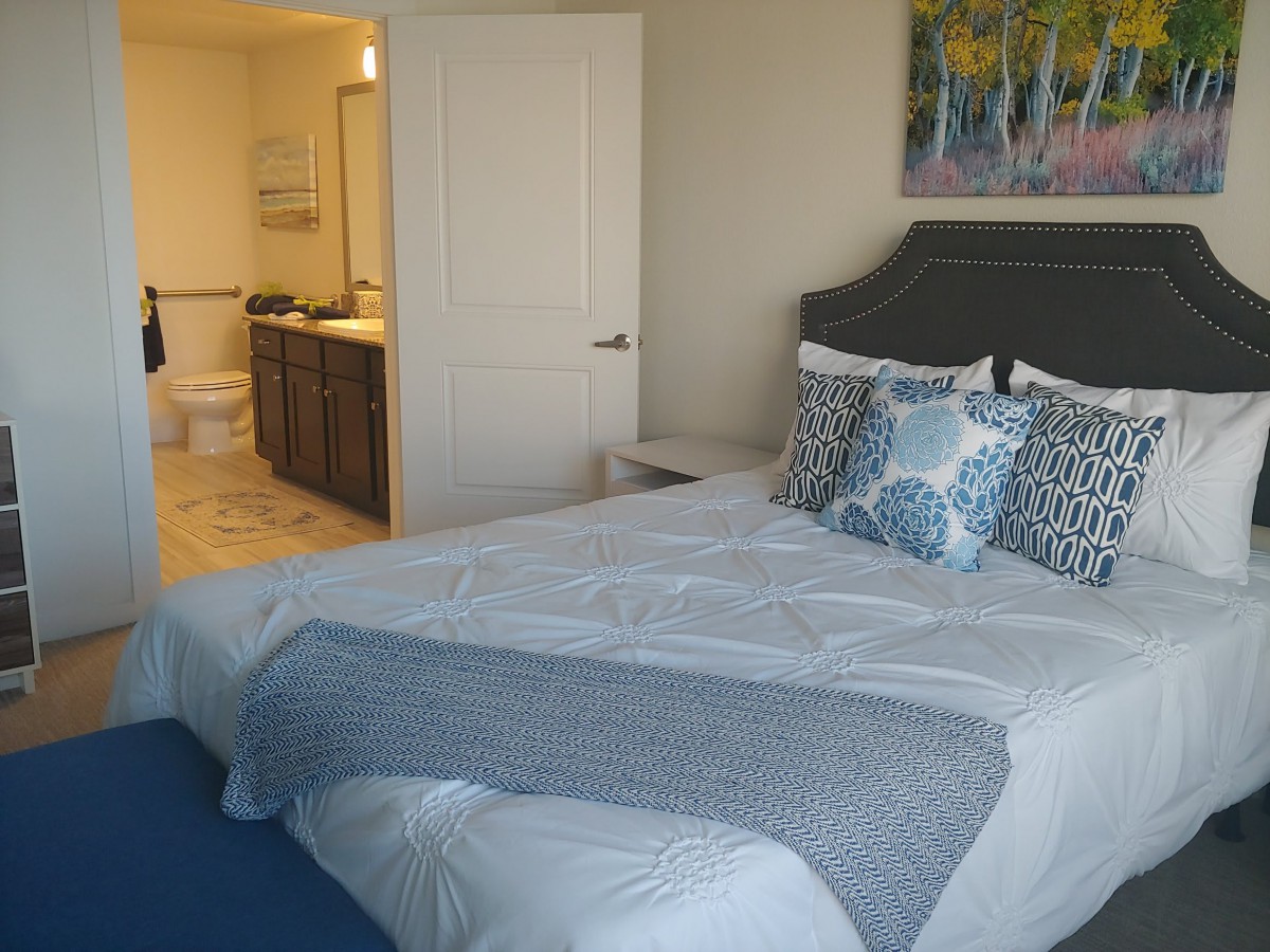 A well-decorated bedroom with a neatly made bed and an adjacent bathroom.