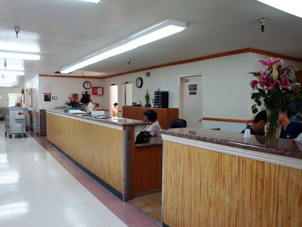 A reception area with people seated and standing at desks in an office environment.