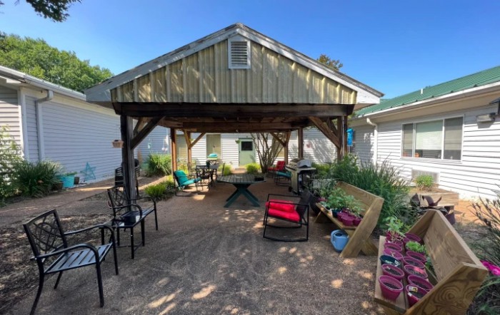 A cozy backyard patio with a wooden gazebo and comfortable seating.