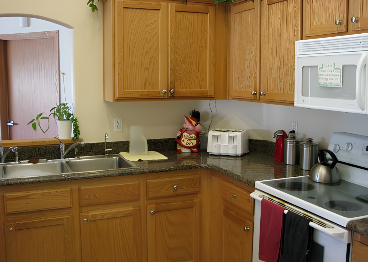 A cozy kitchen with wooden cabinets, various appliances, and a granite countertop.