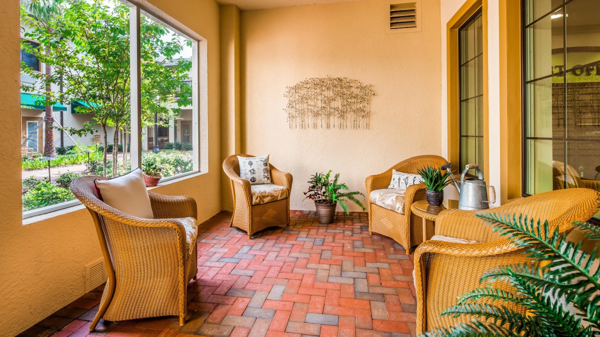 A cozy indoor patio with wicker furniture and potted plants.