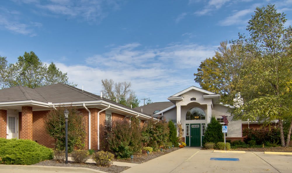 A view of a brick building with a decorative entrance surrounded by greenery.