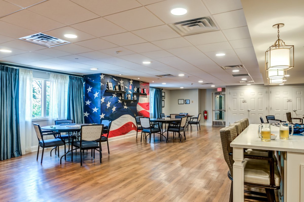 A spacious dining area with tables and chairs, featuring a patriotic flag mural on the wall.