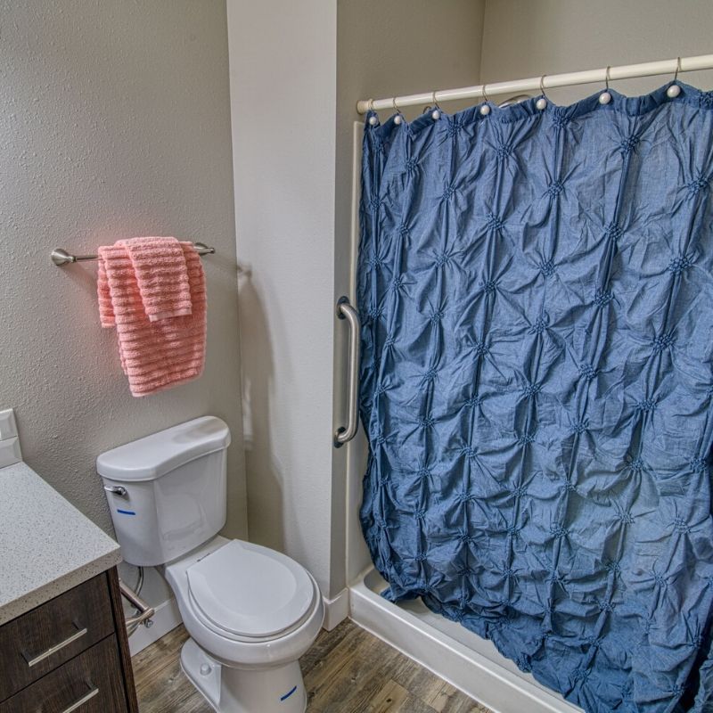 A bathroom featuring a toilet, sink, and a shower with a blue curtain.