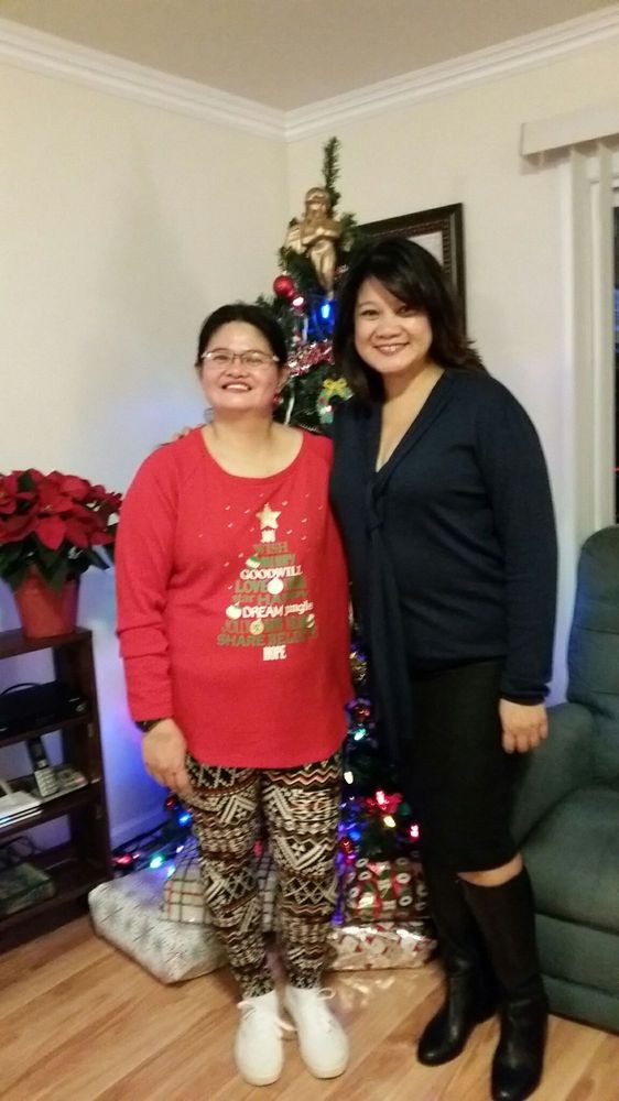Two women posing in front of a Christmas tree with festive decorations.