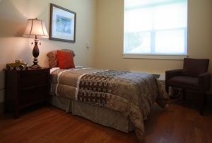 A cozy bedroom with a single bed, lamp, and simple decor.