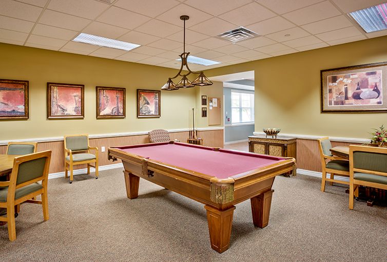 A cozy game room featuring a red-felted pool table under elegant lighting.