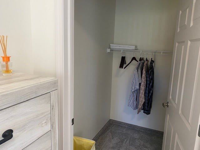A minimalist closet with a few clothes hanging on a rod.