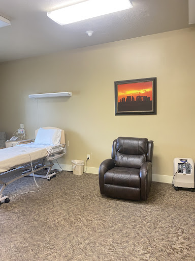 A tranquil patient room featuring a bed, a recliner chair, and calming wall art.
