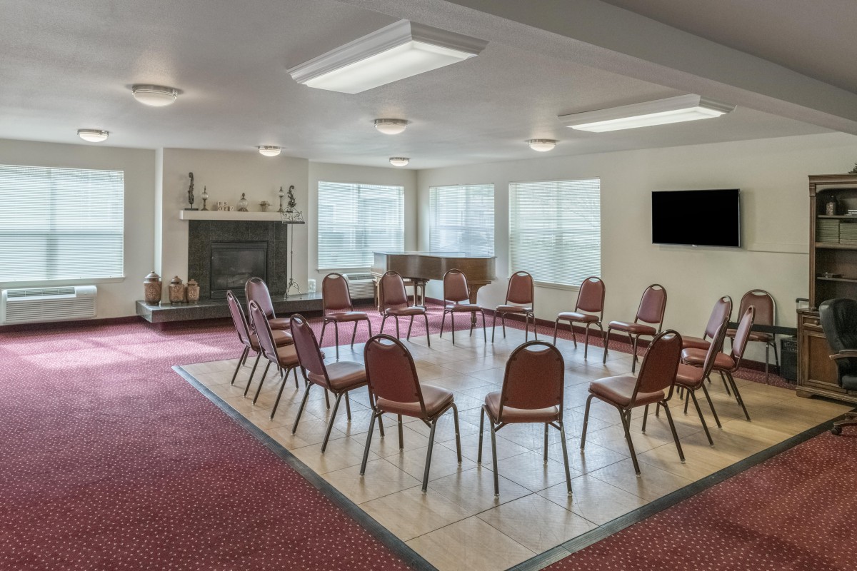 A conference room featuring chairs arranged in a circle with a television and fireplace in the background.