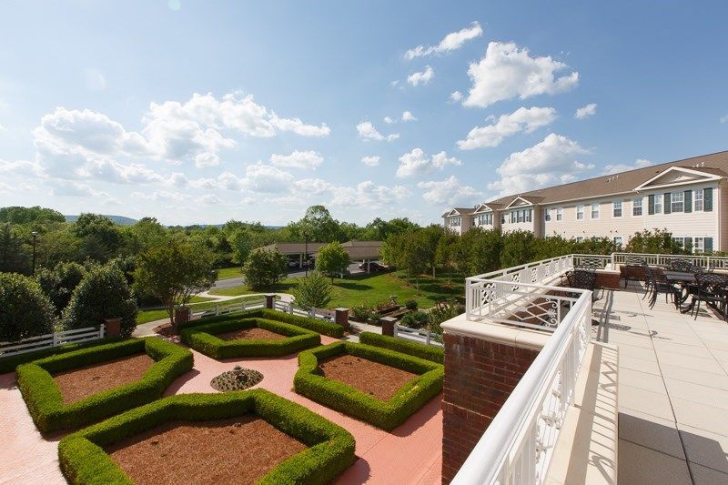 A scenic view from a balcony overlooking a landscaped garden with lush greenery and a partly cloudy sky.
