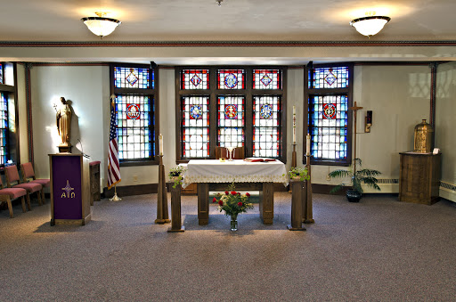 A serene interior view of a chapel featuring an altar and beautiful stained glass windows.