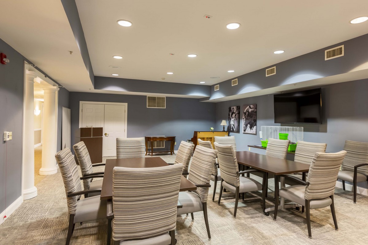 A well-lit modern meeting room with multiple tables and chairs, designed for group discussions or conferences.