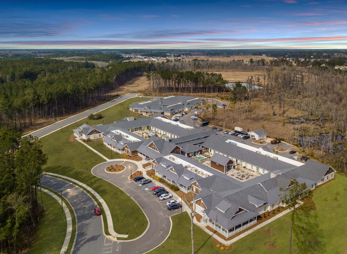 Aerial view of a building complex surrounded by forests and roads.