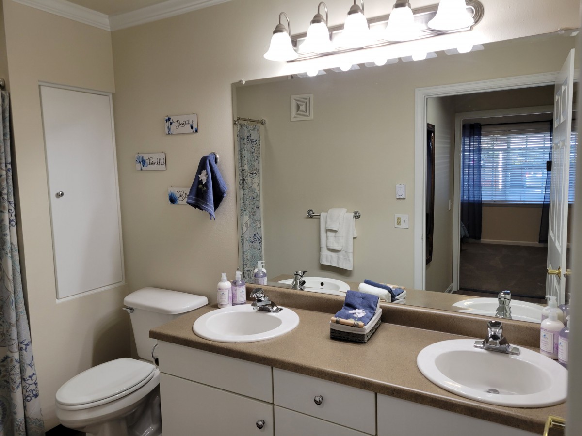 A clean and modern bathroom with double sinks, a large mirror, and ample lighting.