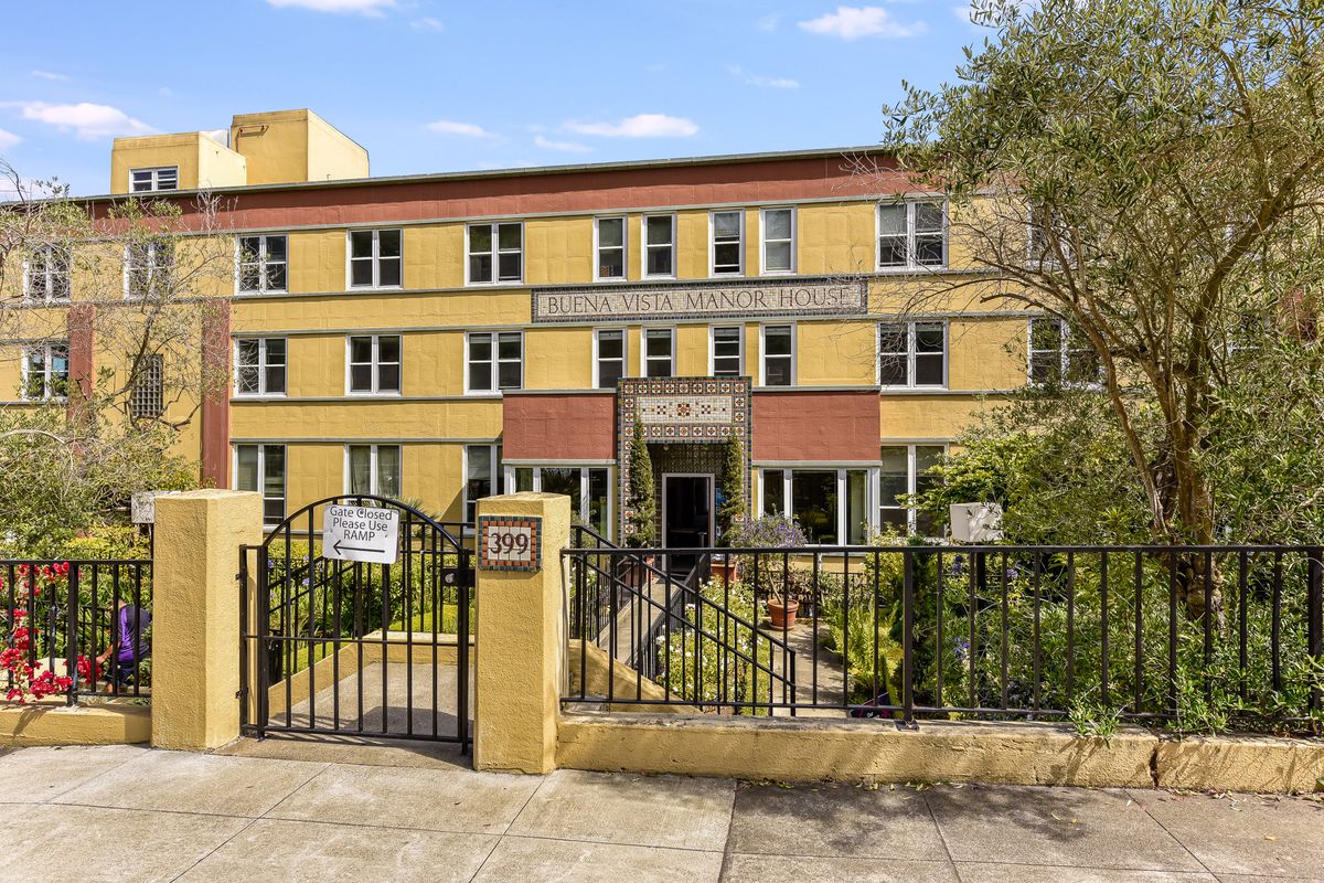 A residential apartment building with a gated entrance and small garden area.