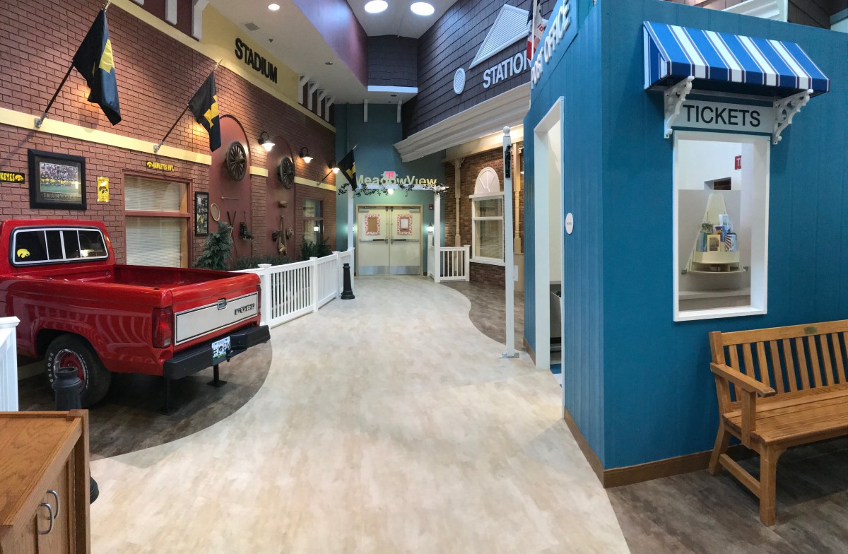 A decorated indoor hallway with shopfronts and a vintage truck display.