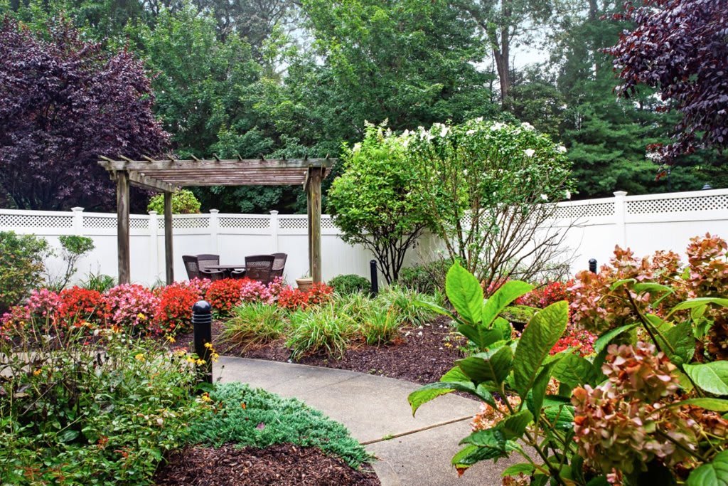 A beautifully landscaped garden with colorful flowers and a pergola providing a shaded seating area.