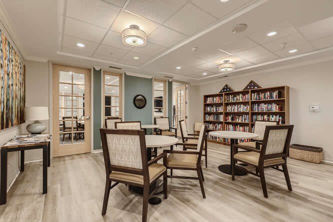 A cozy library with tables, chairs, and bookshelves.