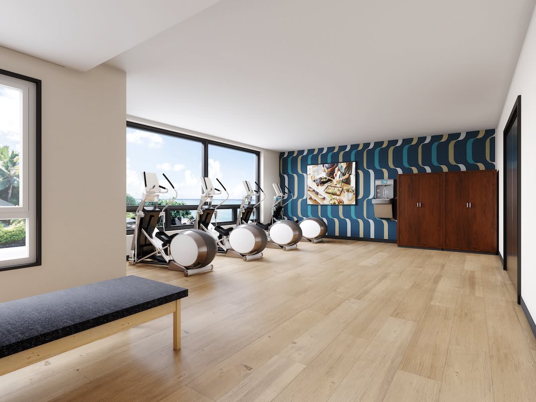 A modern exercise room with stationary bikes, large windows, and wood flooring.