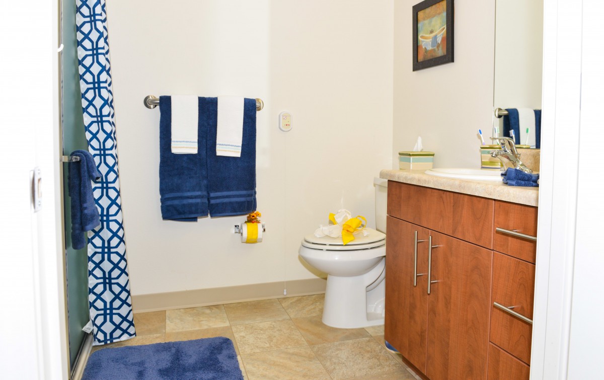A neatly arranged bathroom with blue towels, a shower curtain, and wooden cabinets.