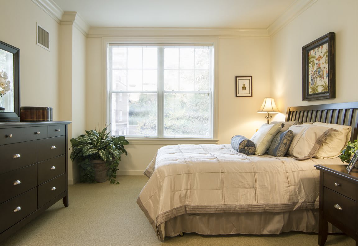 A cozy bedroom with a large window, bed, and decorative elements.