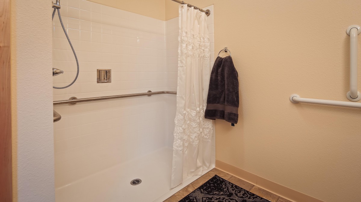 A minimalist bathroom featuring a simple shower with a white curtain and towel hanging on the wall.