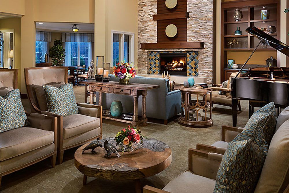 A cozy living room featuring a warm fireplace, surrounded by comfortable seating and elegant wooden tables adorned with decorative accents.