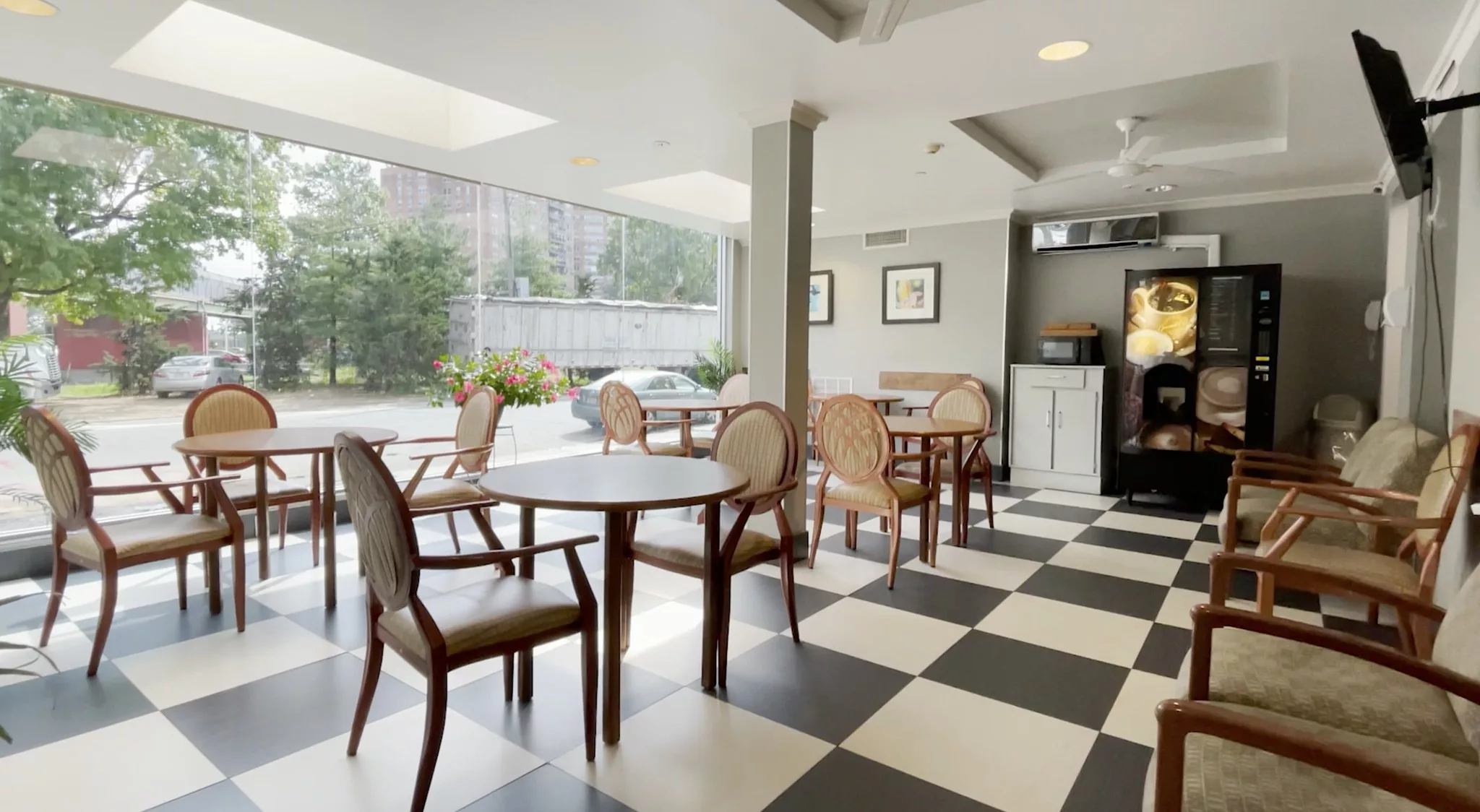 A modern cafe interior with checkered flooring and large windows allowing natural light to fill the space.