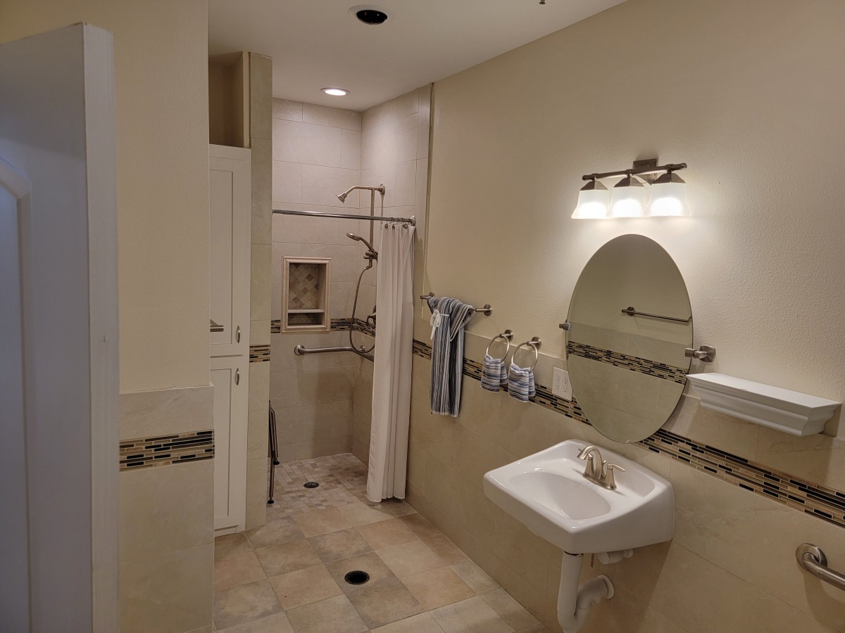 A modern bathroom featuring a walk-in shower, sink, and round mirror with elegant lighting.